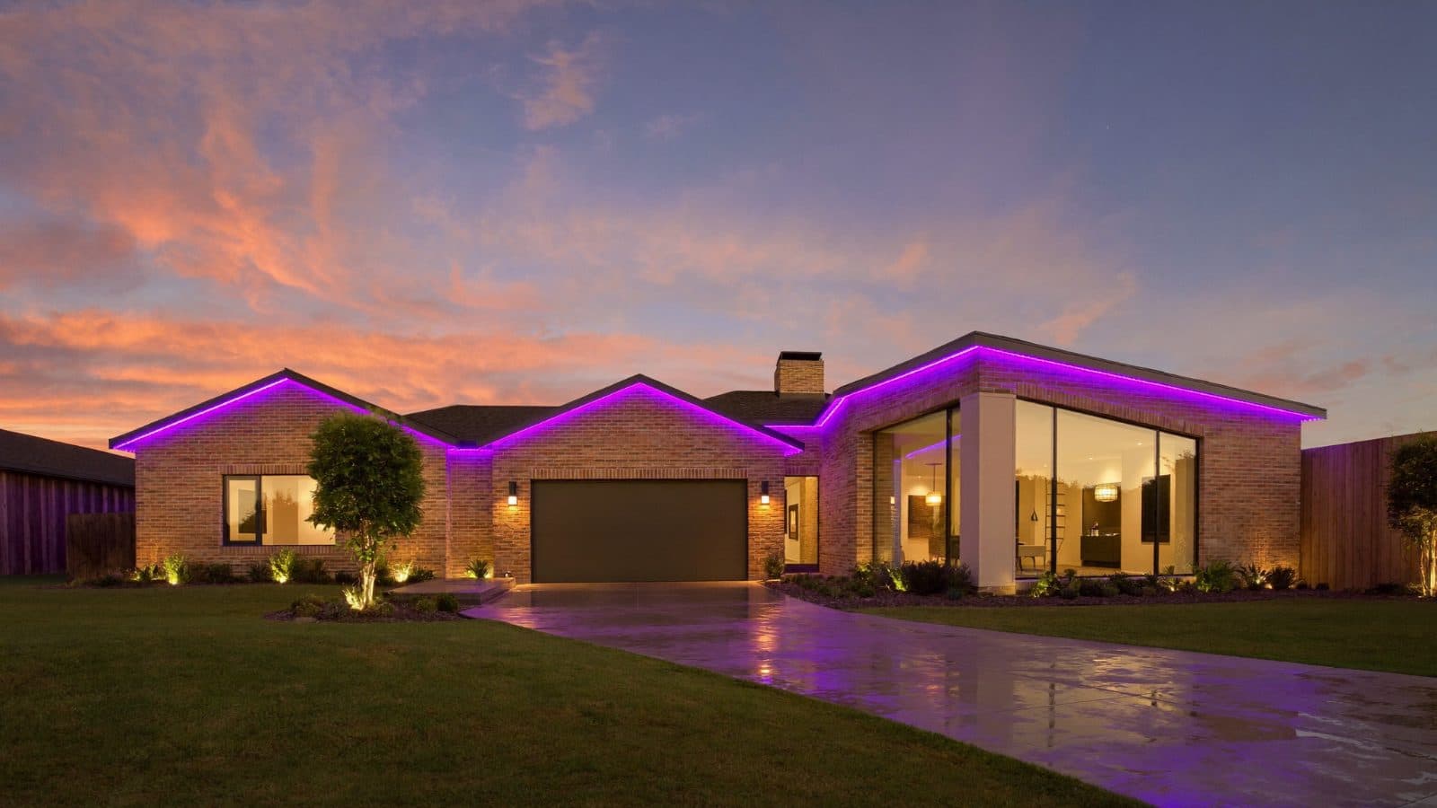 Single-story brick ranch house at twilight with purple LED lighting tracing every roofline edge and gable peak, floor-to-ceiling windows lit from inside
